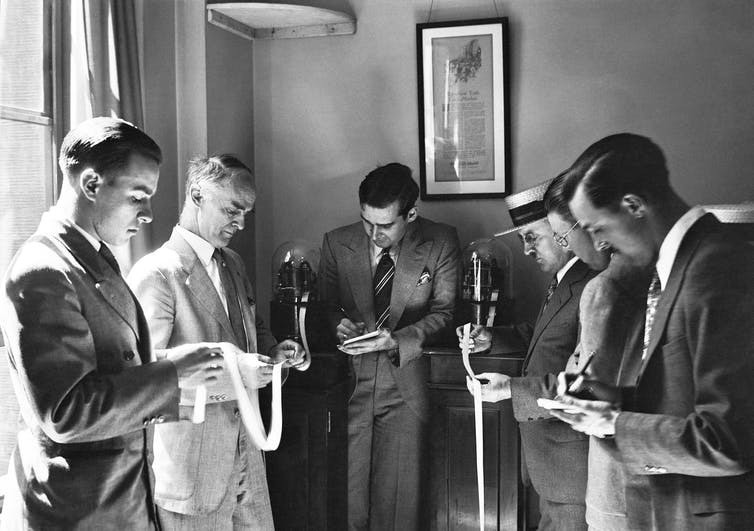 Stockbrokers reading ticker tape in the 1930s